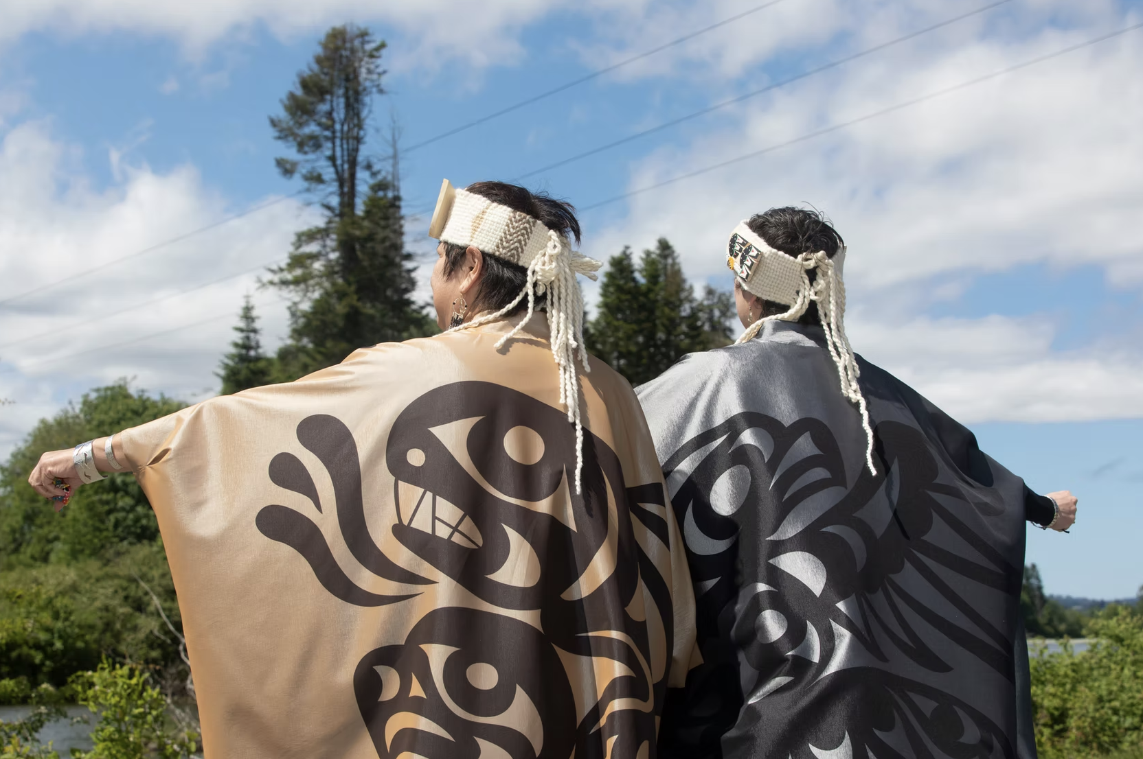 Two people with backs facing camera wearing Ay Lelum clothing pieces